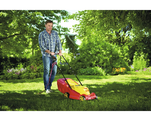 Un homme tond la pelouse avec une tondeuse à gazon dans le jardin.
