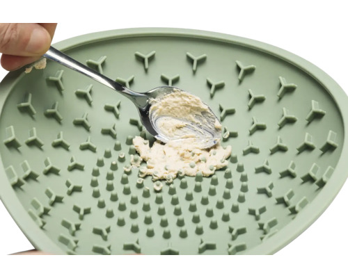 Un moulin à herbes aromatiques vert avec une cuillère et des herbes aromatiques.