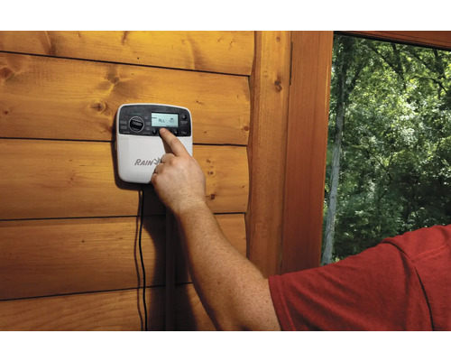 Une personne utilise un ordinateur d''irrigation sur un mur en bois.