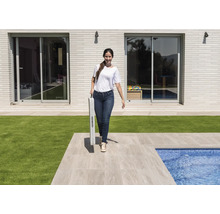 Frau trägt zusammengeklappten Tisch im Garten mit Schwimmbad