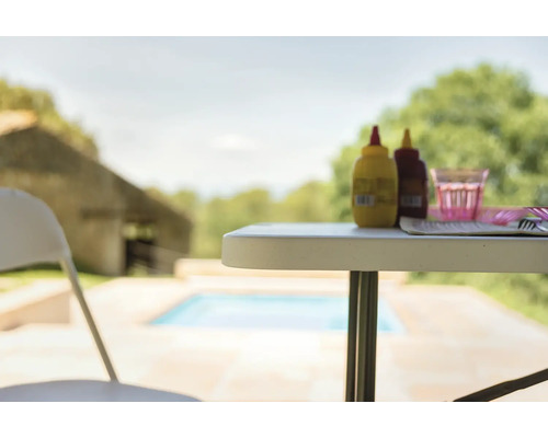 Gartenszene mit Tisch, Stuhl, Soßenflaschen und Geschirr im Freien