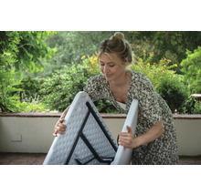 Frau klappt einen klappbaren Gartentisch im Freien zusammen