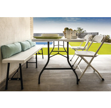 Szene mit Klapptisch, Klappstühlen und Bank mit Kissen auf einer Terrasse