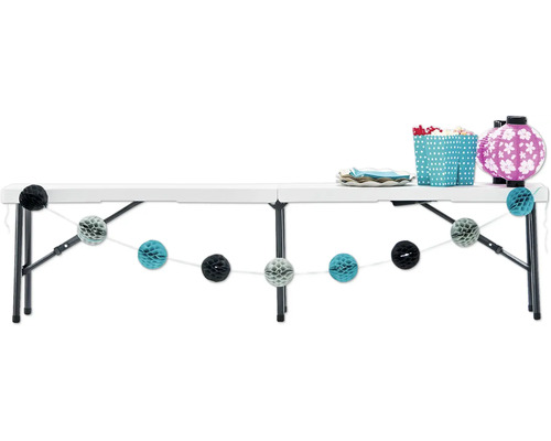 Table pliante blanche décorée avec vaisselle, lanternes et guirlandes