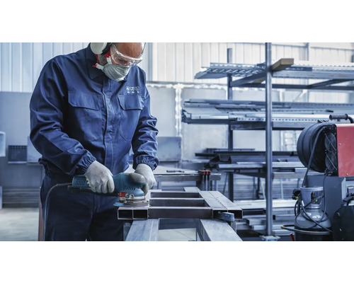 Ein Arbeiter schleift ein Metallstück mit einem Schleifgerät.