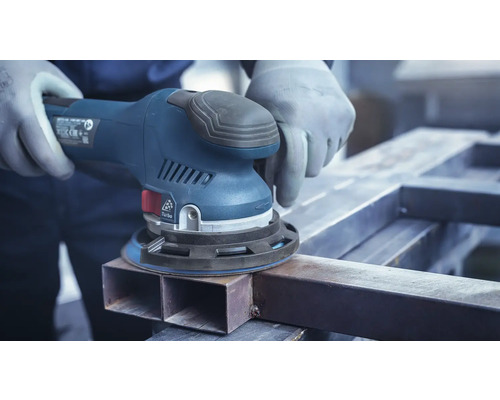 Eine Person schleift ein Metallstück mit einem Exzenterschleifer.