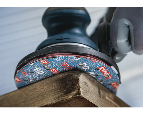 Gros plan d''une ponceuse excentrique ponçant un morceau de bois