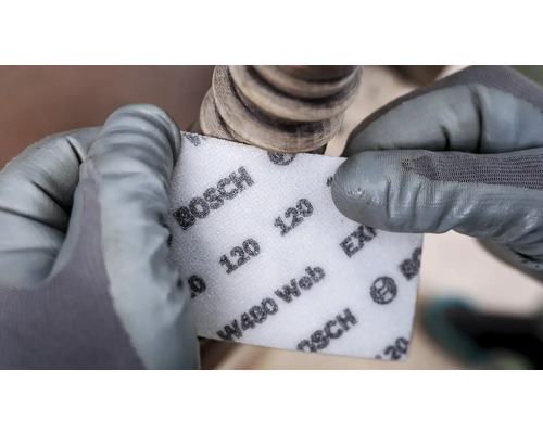 Eine Person schleift mit einem Schleifpad der Körnung 120 von Bosch ein Werkstück.