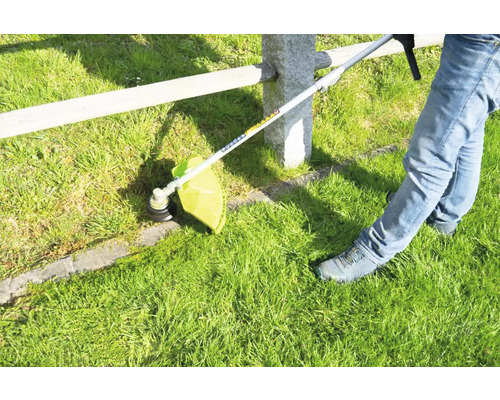 Coupe-bordure en action coupant l''herbe le long d''une clôture.