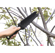 Une main tient une hache de jardin multifonctionnelle utilisée sur une branche