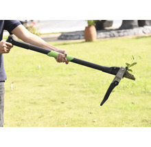 Une personne utilise un désherbeur pour enlever les mauvaises herbes dans le jardin.