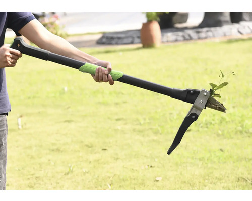 Une personne utilise un désherbeur pour enlever les mauvaises herbes dans le jardin.