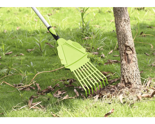 Râteau de jardin pour enlever les feuilles sur la pelouse près d''un tronc d''arbre