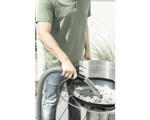 Un homme aspire les cendres d''un gril avec un aspirateur à cendres