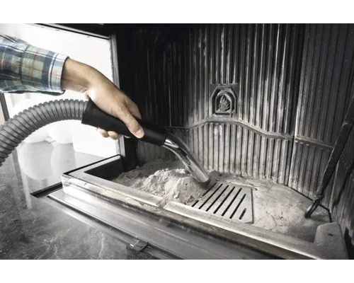 Une personne aspire les cendres d''un poêle à bois avec un aspirateur à cendres