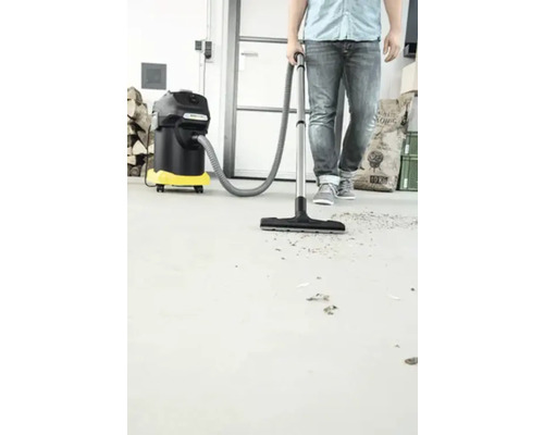 Un homme utilise un aspirateur polyvalent pour nettoyer un sol en béton.