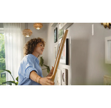 Frau hängt Bilderrahmen an einer Wand auf