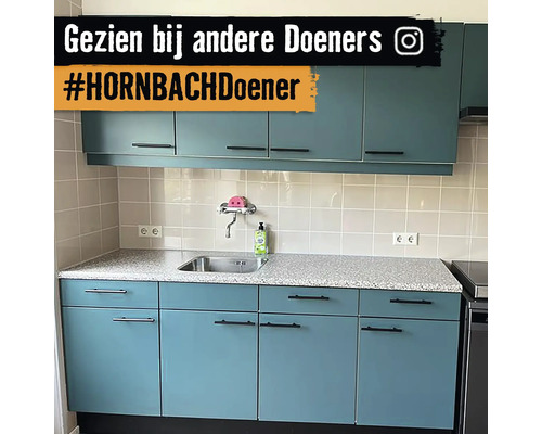 Cuisine avec évier, plan de travail et armoires suspendues dans une pièce lumineuse