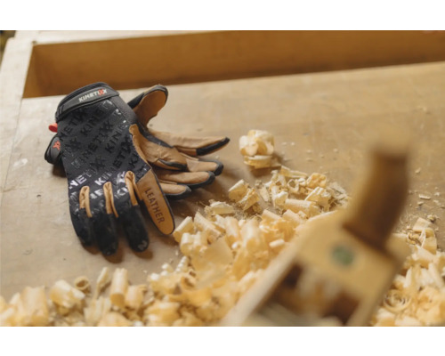 Gants de travail KinetiXx en cuir sur un établi avec des copeaux de bois