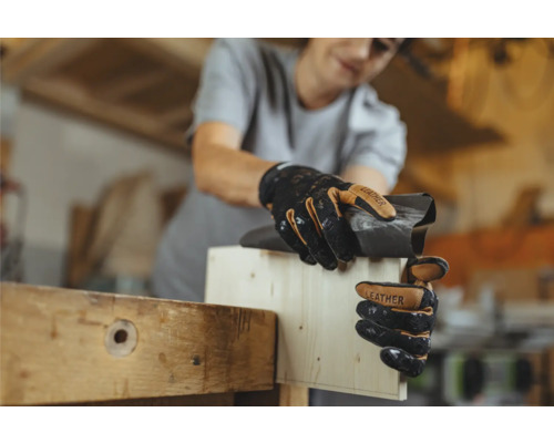 Une femme ponce du bois avec du papier de verre et porte des gants de travail.