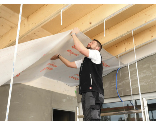 Un homme installe un film de toiture à l''intérieur d''une maison.