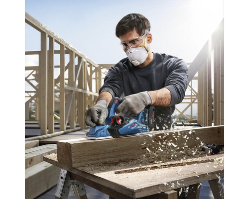 Artisan utilisant un rabot électrique Bosch pour raboter une pièce de bois.