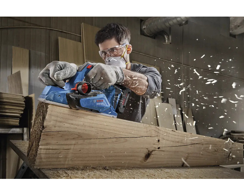 Homme rabotant une planche de bois avec un rabot électrique de marque Bosch