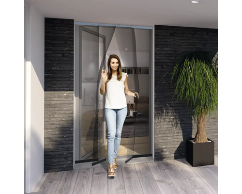 Une femme passe une porte anti-insectes dans une pièce au design moderne