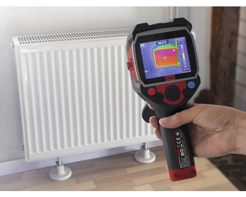 Une main tient une caméra thermique devant un radiateur pour mesurer la température.