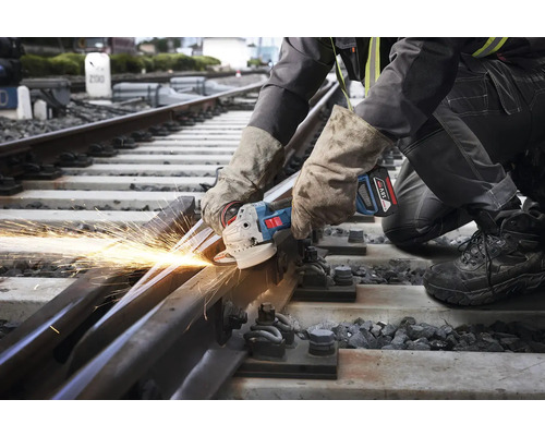 Ein Arbeiter schneidet mit einem Winkelschleifer ein Bahngleis, wobei Funken entstehen.