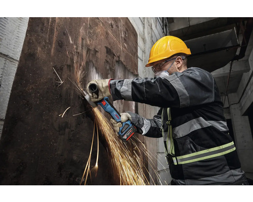 Arbeiter mit Akku-Winkelschleifer beim Schneiden von Metall