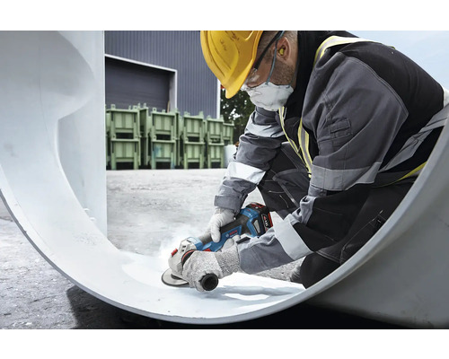 Ein Bauarbeiter bearbeitet ein Rohr mit einem Winkelschleifer