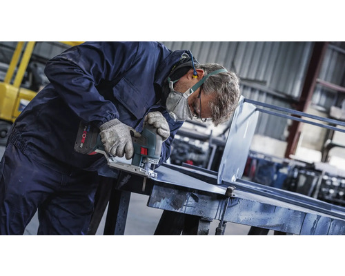 Un artisan coupe du métal avec une scie sauteuse dans un atelier.