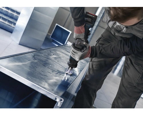 Artisan coupant une tôle avec une grignoteuse.