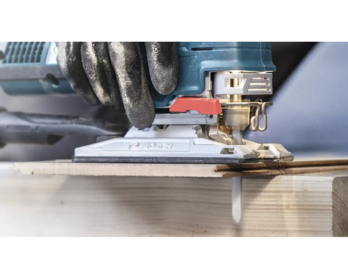 Gros plan d''une scie sauteuse coupant du bois, avec des gants pour les bricoleurs.