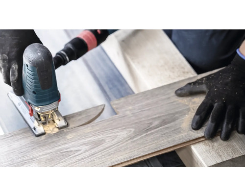 Une scie sauteuse coupe une planche de stratifié.