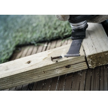 Oszillierendes Elektrowerkzeug schneidet einen Nagel in ein Holzbrett.