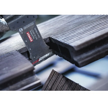 Bosch Logo. Nahaufnahme einer Säge beim Schneiden eines Terrassenbretts.
