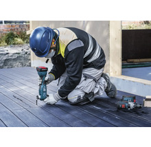 Handwerker kniet auf einer Terrasse und arbeitet mit einem Multifunktionswerkzeug