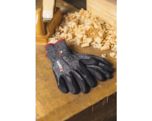Gants de travail KinetiXx sur une surface en bois avec des copeaux et un rabot