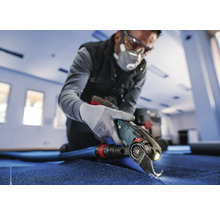 Artisan coupant de la moquette avec un outil électrique
