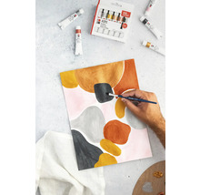 Une personne peint une œuvre d''art abstraite sur papier avec des peintures acryliques, entourée de tubes de peinture et d''une boîte de peinture.