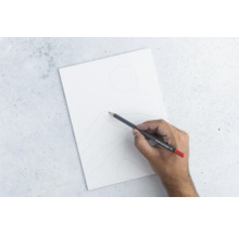 Main dessinant au crayon un paysage de montagne sur une feuille de papier blanche