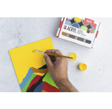 Ensemble de peinture acrylique avec pinceau peignant sur une toile jaune