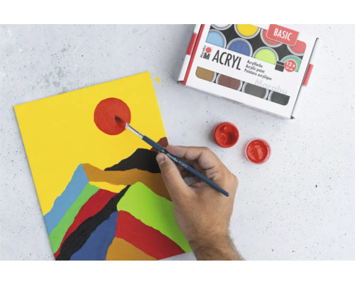 Une personne peint un motif de montagne abstrait avec des peintures acryliques sur une toile, à côté d''une boîte de peintures acryliques.
