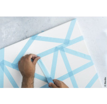 Une personne colle du ruban de masquage sur une toile.