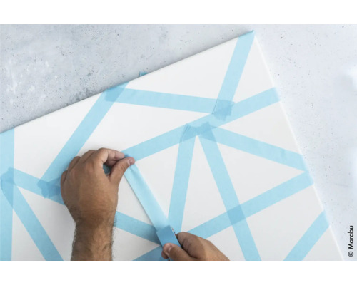 Une personne colle du ruban de masquage sur une toile.