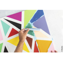 Une personne applique de la peinture avec un couteau sur une toile avec des triangles