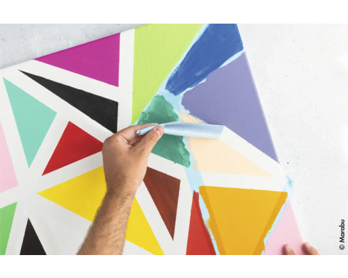 Une personne applique de la peinture avec un couteau sur une toile avec des triangles