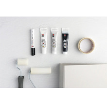 Farbstifte, Farbtuben, Farbroller und Malerkrepp auf hellem Untergrund